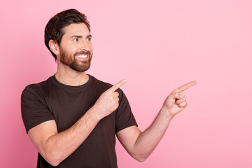 Fototapeta premium Photo of satisfied positive guy with stubble dressed brown t-shirt directing look at offer empty space isolated on pink color background