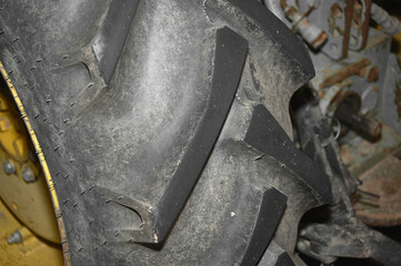 Close-up image of a tractor tire showing its texture and pattern. The tire is mounted on a wheel,...