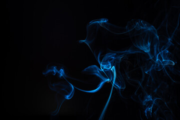 Blue smoke isolated on a black background. A thin curved line of smoke, steam from a burnt candle...