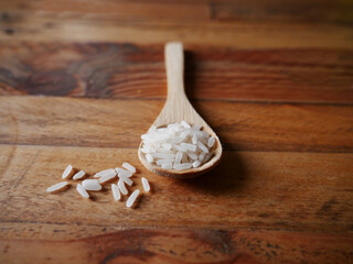 Raw rice grains in a wooden spoon