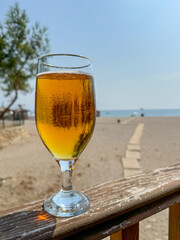 A cold glass of light craft beer stands on a wooden table