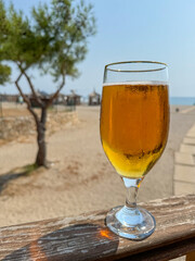 A cold glass of light craft beer stands on a wooden table