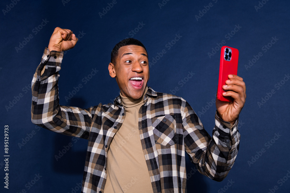 Canvas Prints Photo portrait of nice young man hold device winning wear trendy plaid outfit isolated on dark blue color background