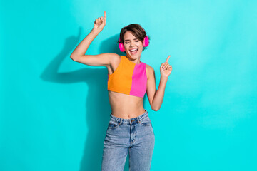 Photo of pretty carefree woman wear pink orange top singing enjoying music headphones dancing isolated teal color background