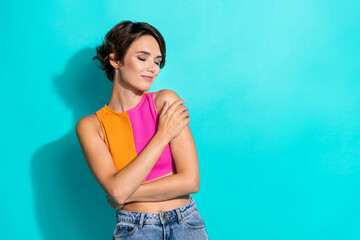 Photo of adorable pretty lady dressed colorful top closed eyes hugging herself empty space isolated turquoise color background