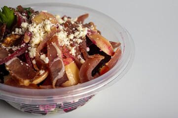 spring summer salad of beets and meat greens in a portable container on a light background, fast food delivery