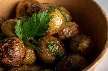 fried new potatoes cooked with golden skin, fast food delivery in kraft paper packaging on a light background, place for inscription, fast food