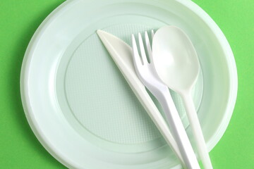 White disposable tableware lies on a green background.