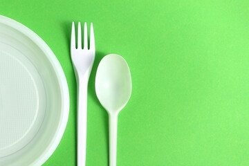 White disposable tableware lies on a green background.