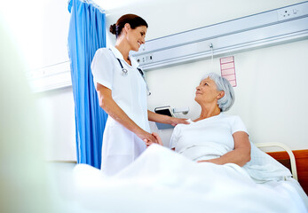 Hospital room, compassion and care of nurse, old woman and communication for health of patient and medical. Clinic, wellness and employee with senior person, holding hands and smile in appointment