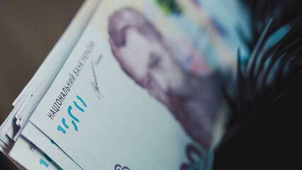 Close up of cash counting machine counting thousand of hryvnia banknotes for currency exchange or investment. Automatic counting equipment for paper money. Ukrainian money bills. Finance and banking.