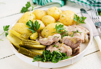 Boiled new potatoes with pieces of stewed pork and pickled cucumbers. Simple food. Country food. Tasty food. Lunch