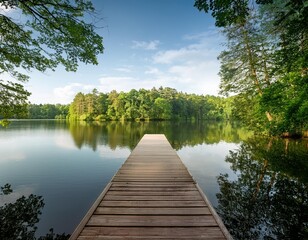 Obraz premium A serene lakeside scene with a wooden dock extending into the calm water, surrounded by lush