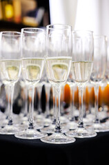 Rows of Champagne Flutes Ready for Celebration. Rows of champagne flutes filled with sparkling champagne, arranged on a table, prepared for a festive event. Vertical shot.