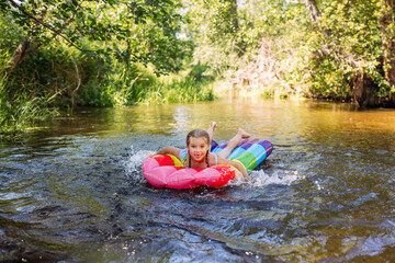 a girl child swims in the water of the river inflatable mattress laughter joy splashes summer heat