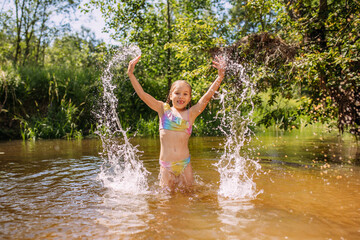 a girl child bathes in the water of the river laughter joy splashes summer heat