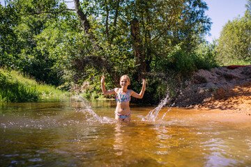 a girl child bathes in the water of the river laughter joy splashes summer heat