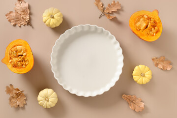 Autumn pumpkins, fall leaves, empty baking dish. Concept cook Pumpkin pie on beige background. Top view. Thanksgiving Day.