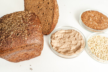 Rye bread with cumin on a white background and bowls with ingredients. Selected focus.
