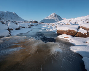 Waterfall in winter on the River Etive and a snow bank at in Glencoe in the Scottish Highlands. High quality photo
