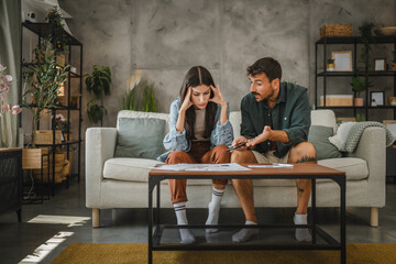 Adult angry couple sit and calculate their monthly domestic finances