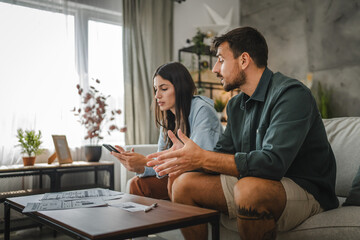 Adult angry couple sit and calculate their monthly domestic finances