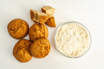Small buns on a white table and a bowl with a mixture to make them. Selected Focus