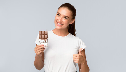 Chocolate Lover. Girl Holding Choco Tablet Gesturing Thumbs Up Standing Over White Background....