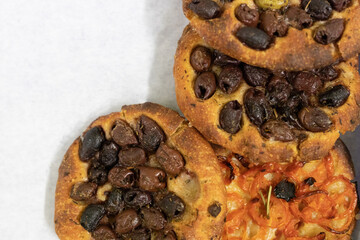 A close up of focaccia bread topped with olives and tomatoes