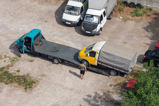 Loading a small inoperable truck onto a tow truck in a parking lot