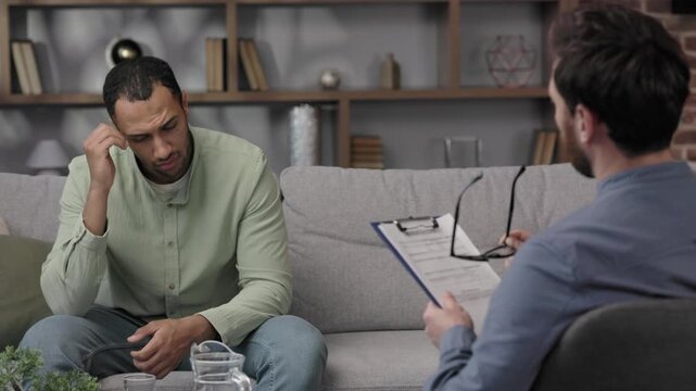 A visit to an African American psychologist. A man sits on a couch and talks to a psychotherapist. Depression, apathy, stress, burnout at work. Help of a psychologist.