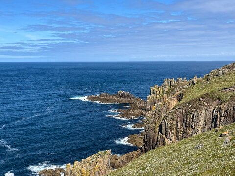 A beautiful cliff rises majestically above the ocean, its rugged rocks contrasting with the deep blue waters below. 