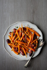 A large platter serving dish of glazed and roasted carrots with fresh thyme and honey