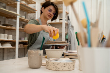 Cleaning a sponge tool before smoothing the surface of a pottery project. Washing off the sponge before applying moisture on a clay product.