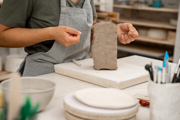 Wire clay cutter to cut clay from a large block. Cutting off the necessary piece of clay before forming a pottery product. Learning how to cut clay on ceramics workshop.