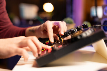 Young artist creating new music in editing post production, twisting pre amp knobs on mixing console. Skilled composer singer adjusting volume levels in post production. Close up.