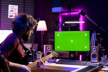 Young musician learning to play acoustic guitar with online lessons via computer with greenscreen...