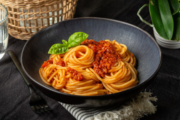 Dinner with a plate of Spaghetti with vegan bolognese sauce made from soya, tomato and vegetables. Vegetarian pasta. Light table surface.