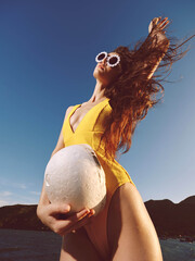 Ocean, woman, yellow swimsuit a beautiful woman in a yellow swimsuit holds a coconut up in the air,...