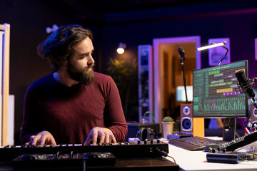 Music producer playing electronic piano keyboard in home studio, recording midi controller notes to create new songs. Young artist producing synthesizer keys, post production techniques.