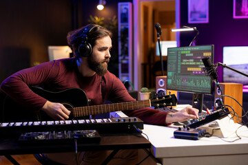 Singer creating tunes on guitar and adding sound effects in post production, uses mixing console...