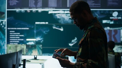 Cybersecurity specialist operates in a high tech military control center, monitoring surveillance footage and gathering intelligence for a new defense mission. Secret service activity. Camera B.