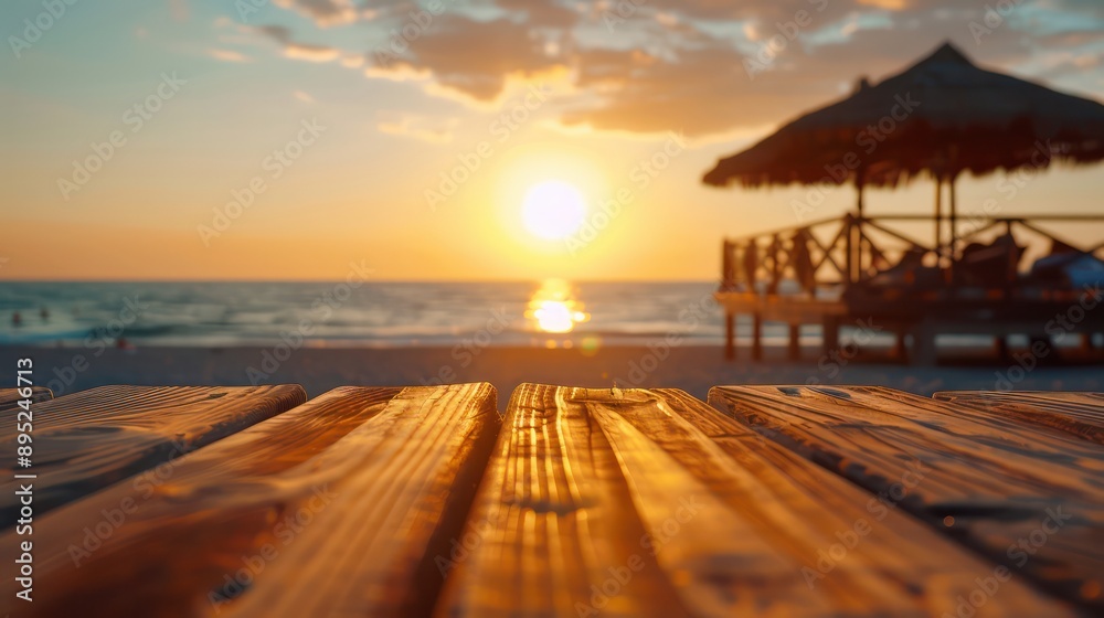 Fototapete a wooden table with a view of the ocean and a beach umbrella. the sun is setting in the background