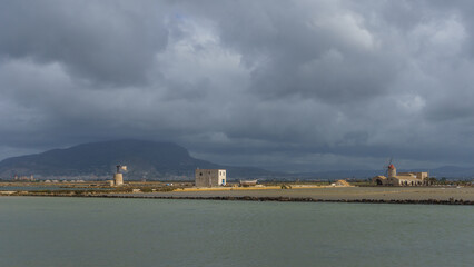 Nature reserve of Saline di Trapani with salt fields, Salt Museum and windmill on a cloudy morning, Contrada Nubia, Sicily, Italy