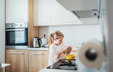 Young girl concentrates on preparing potato dish in sleek modern kitchen. She cleaning potato with peeling knife cozy atmosphere, highlighting the joys of culinary creativity at home.