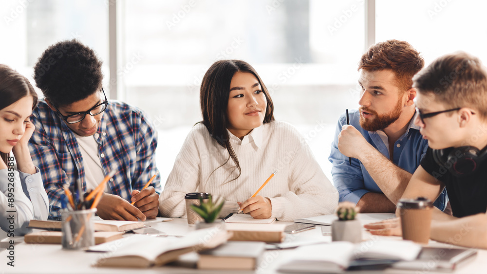 Leinwandbilder a diverse group of students sitting together at a table, engaged in conversation and possibly doing 