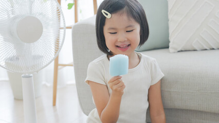 夏休みに扇風機の前でアイスを食べる子供
