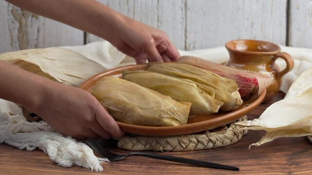 Latin woman shows a traditional clay dish with tamales of different flavors Mexican cuisine