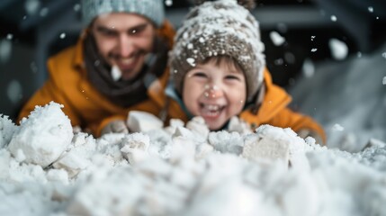 A father and child dressed warmly in jackets, happily engaging in snow play with big smiles on their faces, capturing a moment of pure joy and family bonding.