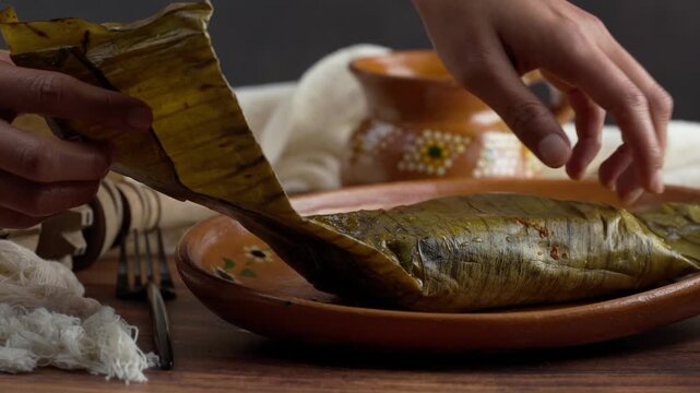 Latin woman unwraps a Jarocho tamale with pork and red sauce, Mexican food
